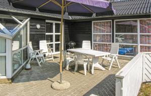 a patio with a table and chairs and an umbrella at Nice Home In Glesborg With Sauna in Fjellerup Strand