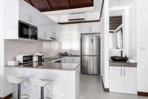 a white kitchen with a refrigerator and stools in it at Renovated Luxury 3 Bed Pool Villa Kirikayan Maenam Koh Samui in Amphoe Koh Samui