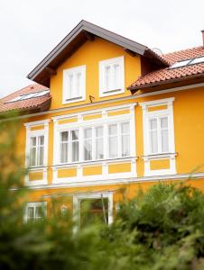 ザルツブルクにあるヴィラ チェコニ バイ ダス グリューネ ホテル ツア ポスト 100% ビオの白窓と木々のある黄色い家