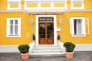 a yellow house with a wooden door and stairs at Villa Ceconi by Das Grüne Hotel zur Post - 100% BIO in Salzburg