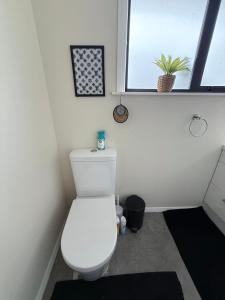 La salle de bains est pourvue de toilettes blanches et d'une fenêtre. dans l'établissement Pet friendly house with hot tub, à Lower Hutt 3 autres photos