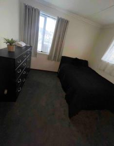 une chambre avec un lit noir et une commode dans l'établissement Pet friendly house with hot tub, à Lower Hutt