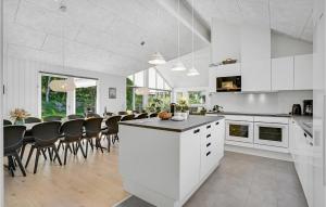 a kitchen with white cabinets and a table with chairs at Beautiful Home In Væggerløse With Sauna in Marielyst +25 photos