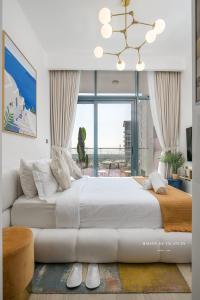 a white bedroom with a large bed and a chandelier at Santorini Studio Pool View in Dubai