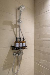 a shower with four bottles of essential oils on a shelf at Santorini Studio Pool View in Dubai
