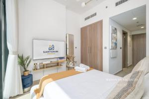 a bedroom with a bed and a flat screen tv at Santorini Studio Pool View in Dubai