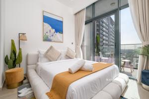 a bedroom with a white bed and a couch at Santorini Studio Pool View in Dubai