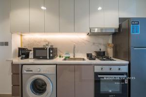 a kitchen with a sink and a washing machine at Santorini Studio Pool View in Dubai