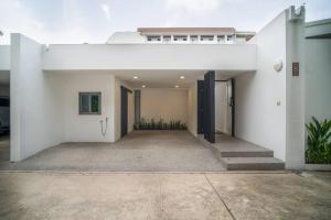 a large white house with a driveway at Modern Tranquillity Pool Villa, Layan in Laguna Phuket