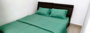 a bed with green pillows in a room at Cozy Homestay in Ipoh