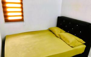 a bed with two yellow pillows in a room at Cozy Homestay in Ipoh