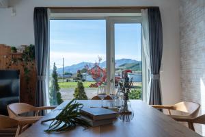 een eetkamer met een tafel en een groot raam bij Clematis in Nakafurano