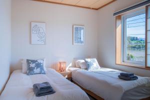 twee eenpersoonsbedden in een kamer met een raam bij Clematis in Nakafurano