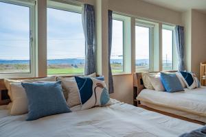 twee bedden in een kamer met ramen bij Clematis in Nakafurano