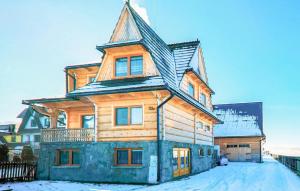 a wooden house with a gambrel roof in the snow at 2 Bedroom Amazing Apartment In Ratulow in Ratułów