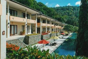 a hotel with a pool and umbrellas next to a building at Kebun Villas & Resort in Senggigi
