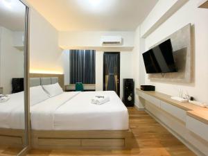 a hotel room with a bed and a flat screen tv at Comfort and Cozy Stay 1BR at The Alton Apartment By Travelio in Semarang +5 photos