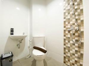 a bathroom with a toilet and a sink and a shower at Comfort and Cozy Stay 1BR at The Alton Apartment By Travelio in Semarang