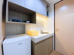 a small kitchen with a sink and a refrigerator at Comfort and Cozy Stay 1BR at The Alton Apartment By Travelio in Semarang