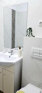 a white bathroom with a sink and a mirror at Isabell Home in Iaşi