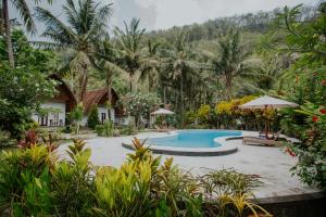 a resort with a swimming pool and palm trees at Crystal Bay Villa in Nusa Penida