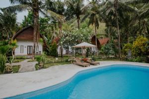 a pool in front of a house with palm trees at Crystal Bay Villa in Nusa Penida
