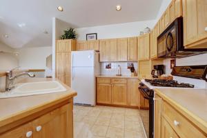 a kitchen with wooden cabinets and a white refrigerator at 172 Sauterne Sanctuary Townhouse in Silverthorne +38 photos