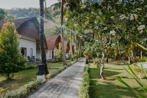 a walkway in front of a house with palm trees at Crystal Bay Villa in Nusa Penida