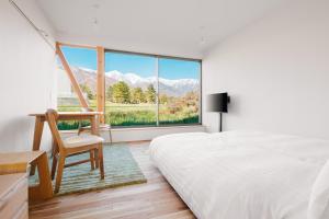 a bedroom with a bed and a chair and a window at Passage LODGE Hakuba in Hakuba