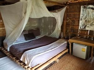 a bed with a mosquito net in a room at ecolodge khamu homestay guesthouse in Ban Pak Ing