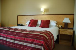 a hotel room with a large bed with red pillows at Magherabuoy House Hotel in Portrush