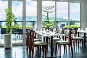 a dining room with tables and chairs and windows at ESPERO INN Malappuram in Malappuram