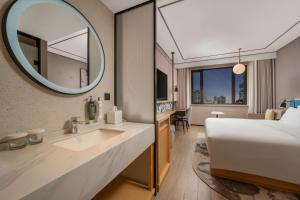 une chambre d'hôtel avec un lit et un miroir dans l'établissement Hilton Garden Inn Shanghai Caoyang, à Shanghai