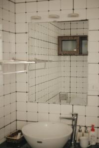 un bagno piastrellato bianco con lavandino e specchio di HIDDEN GEM*HEART of THE OLD QUARTER*5BR*FULL HOUSE a Hanoi