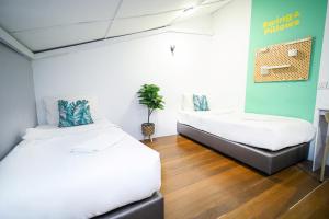 a bedroom with two beds and a potted plant at Swing & Pillows @ Beach Street in George Town +33 photos