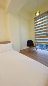 Un dormitorio con una cama y una silla y una ventana. en 古栗House-2至6人包層公寓民宿, en Taitung