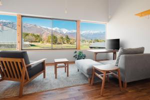 a living room with a large window with mountains at Passage LODGE Hakuba in Hakuba