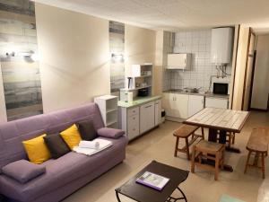 a living room with a purple couch and a kitchen at Apartamentos La Cabaneta Mikka 3000 in Pas de la Casa
