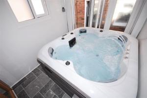 une baignoire remplie d'eau bleue dans une salle de bain dans l'établissement Cozy Hideaway With Hot Tub Sauna Sleeps 7, à Falmer 44 autres photos