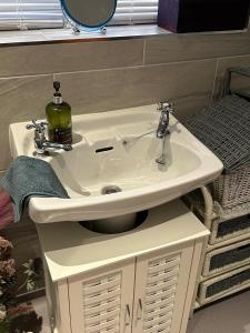 a white bathroom sink with a soap dispenser on it at Shropshire Guestroom in Wolverhampton +21 photos