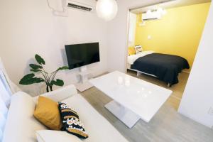 a living room with a white couch and a bed at Stellar西糀谷202 in Tokyo