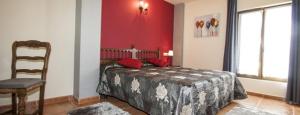 a bedroom with a bed with a chair and a red wall at El Pradón in Mar