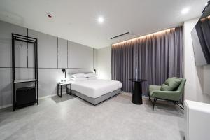 SeosanSeosan Hotel Posto的卧室配有白色的床和绿色椅子