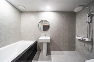 SeosanSeosan Hotel Posto的带水槽、浴缸和镜子的浴室