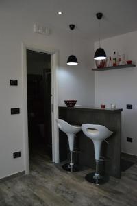 a kitchen with a bar with two white stools at B&B O Casteddu in Monforte San Giorgio