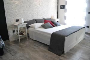 um quarto com uma grande cama branca e uma parede de tijolos em B&B O Casteddu em Monforte San Giorgio