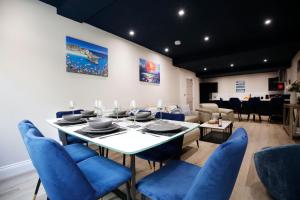 a dining room with a white table and blue chairs at Oceania Suites in Blackpool