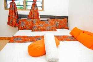 1 dormitorio con 2 camas con almohadas de color naranja en African themed one bedroom, en Diani Beach