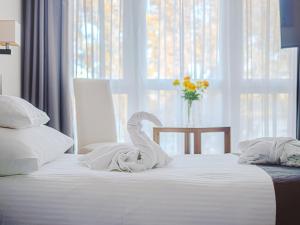 a white bed with a swan decoration on it at Holiday Beach Budapest Wellness Hotel with Sauna Park in Budapest