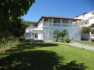 a large blue house with a lawn in front of it at Lazanis Studios Apartments in Laganas